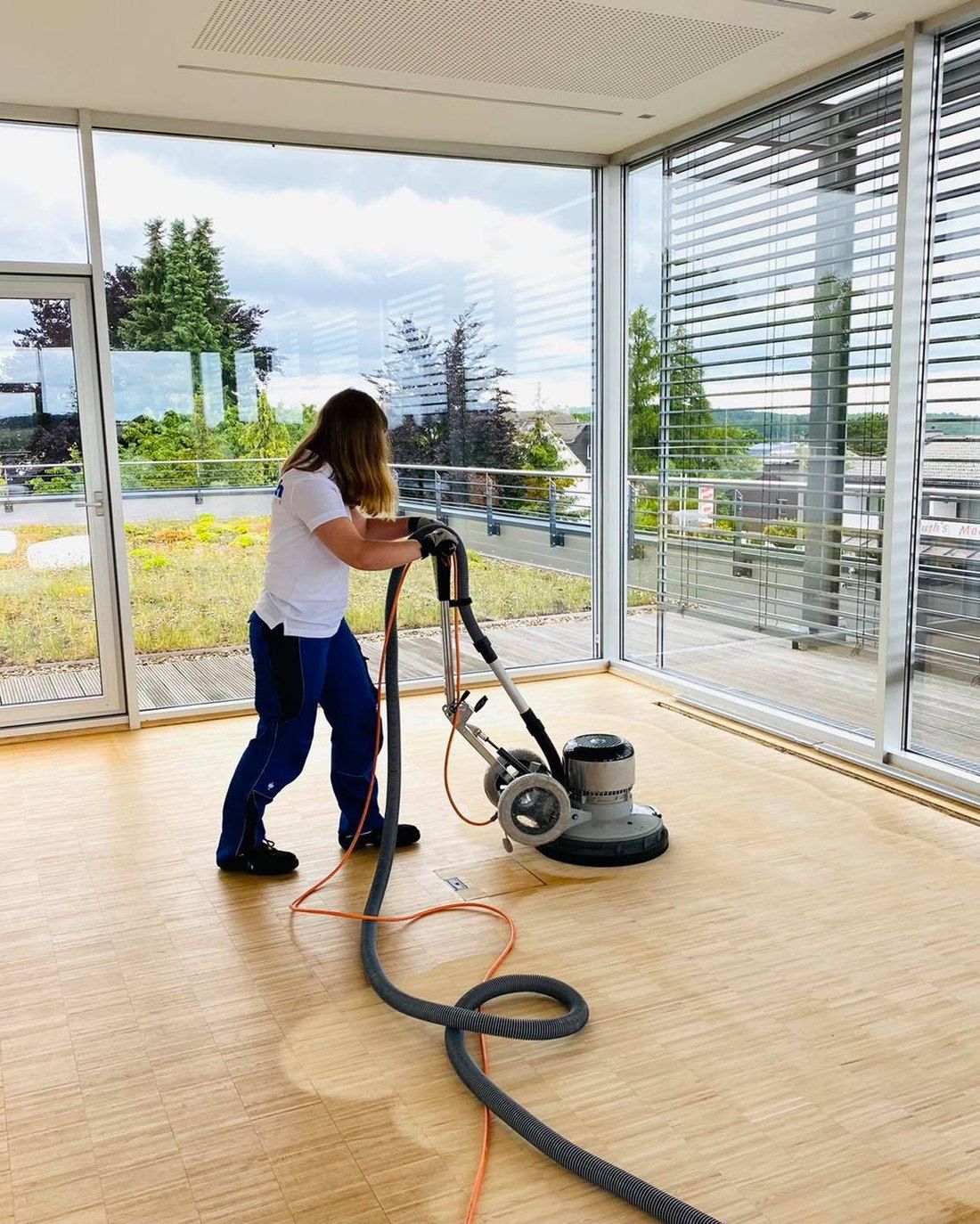 Limbach-Mitarbeiterin reinigt einen Holzboden mit der Einscheibenmaschine